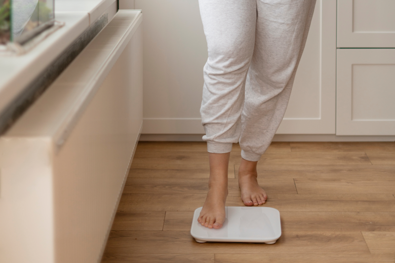 A woman is standing on a scale after looking up how to lose weight in Charleston, SC.